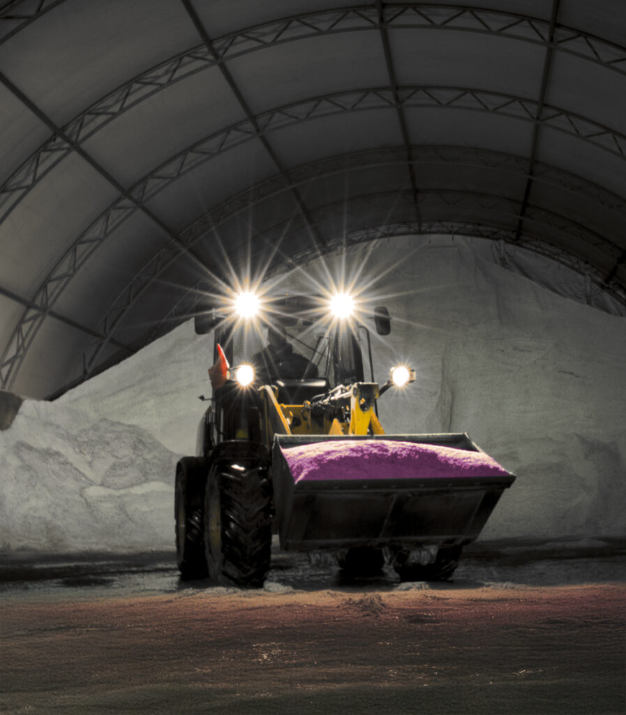 Hot Pink De-icer in tractor in front of pile of snow